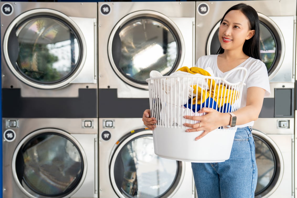 Happy Asian cleaning woman doing laundry in a laundry shop.